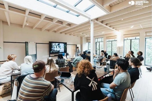 Participants réunis autour d’une présentation dans une salle lumineuse.