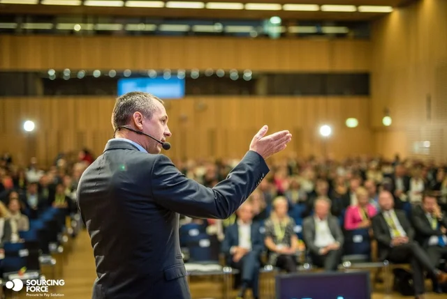 Intervenant devant un public en conférence.
